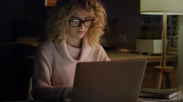 Handheld video of woman working on laptop late at home. Shot with RED helium camera in 8K.