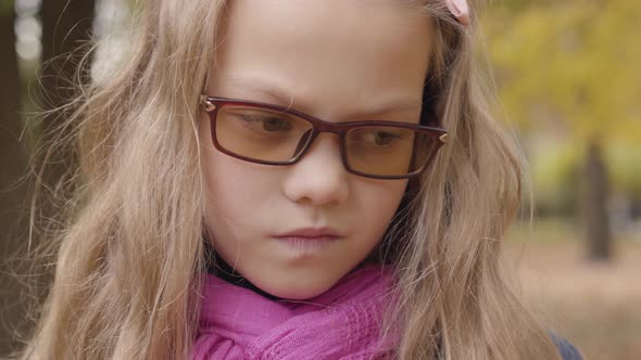 Close-up Portrait of a Sad Caucasian Teenage Girl Standing in the Autumn Park