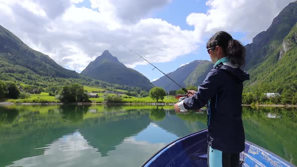 Woman on the Boat Catches a Fish on Spinning in Norway