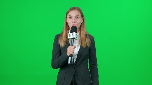 Female News Reporter Speaks Into a Microphone on a Green Background and Looks Into the Camera