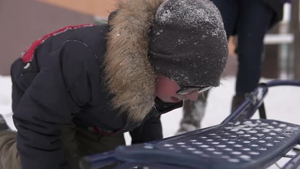 Happy child in winter licked the metal sled with his tongue. Winter fun for children.