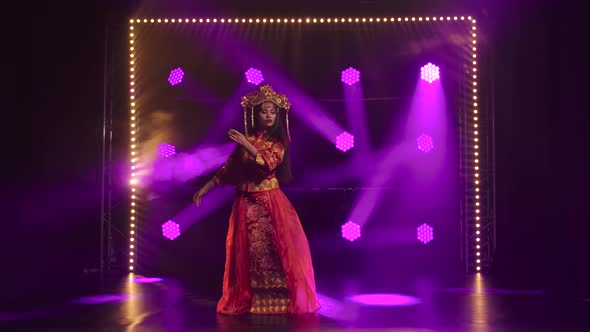 Young Woman Dancing in a Dark Studio with Smoke and Purple Neon Lights. Female Dancer in Red Silk