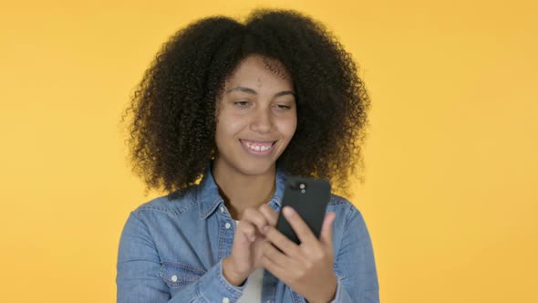 African Woman Using Smartphone, Yellow Background 