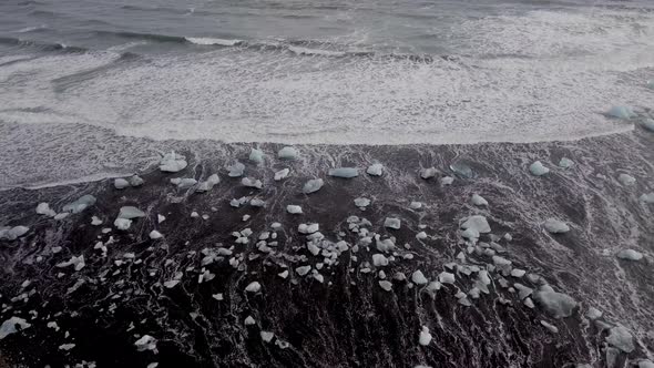 Aerial view of black sand beach with iceberg ice pieces on the shore also cal