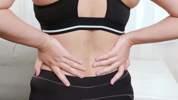 Women suffering from back pain and massaging aching muscles and self massage by her hand. Healthcare