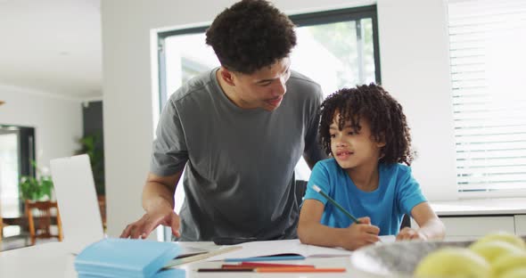 Happy biracial man and his son doing homework together