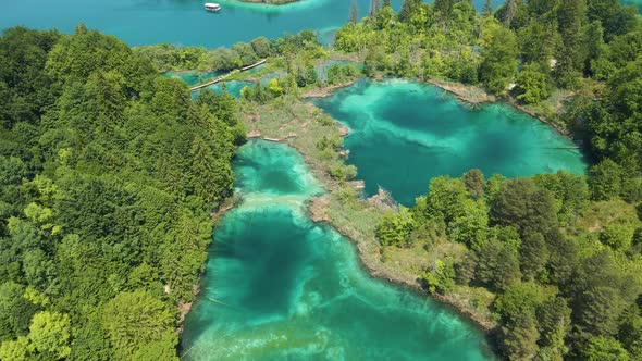 Top view of the Plitvice Lakes National Park with many green plants, beautiful lakes and a boat sail
