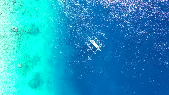 Wide flying tourism shot of a sandy white paradise beach and blue water background in high resolutio