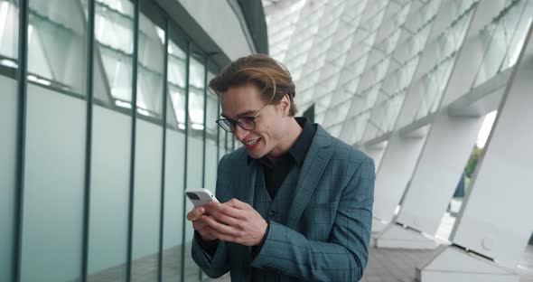 Happy Excited Handsome Man Businessman in Formal Suit Looking at Smartphone Shocked By Great News