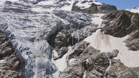 Glacier Covered with Stone Rocks Deep Cracks and Small Waterfalls