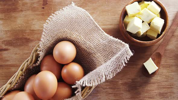 Brown eggs and butter cubes on wooden table