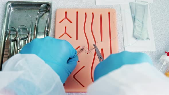 Surgeon trains to apply stitches on a special silicon pad, medical attributes