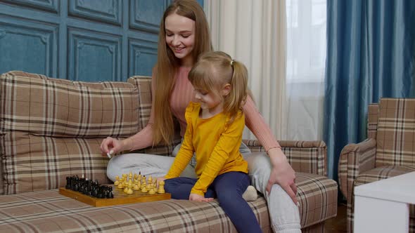 Small Cute Daughter Child and Young Mother Playing Chess at Home Sofa Leisure Hobbies Activities