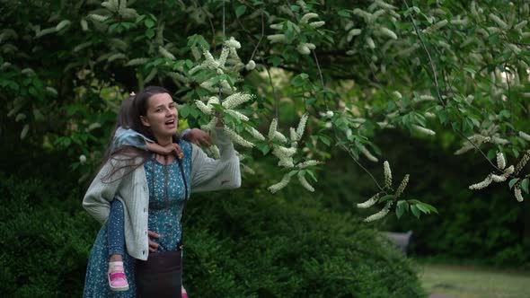 Happy Family Mother with Daughter Little Kid Have Fun Sniffing Flowers on Trees Enjoying Summer