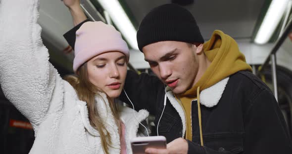 Close Up View of Happy Couple Laughing While Sharing Headphones. Millennial Guy and Girl Using Phone