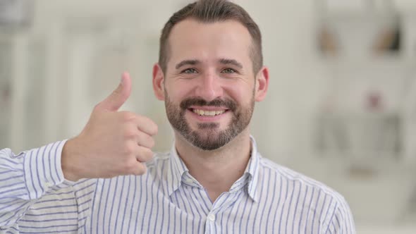 Portrait of Positive Young Man Doing Thumbs Up