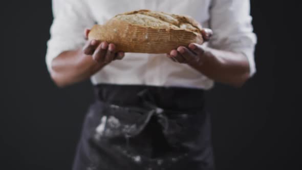 Video of cook holding loaf of bread on black background