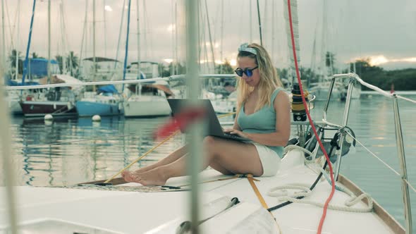 Gorgeous Lady Is Smiling While Using a Laptop on a Sailboat