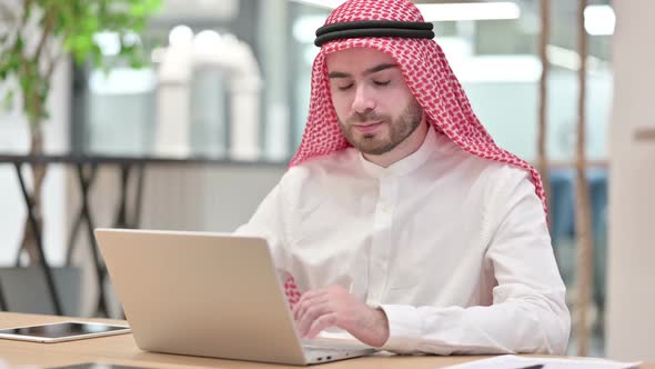 Arab Businessman with Laptop Smiling at Camera in Office