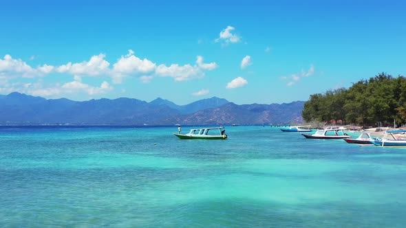 Wide angle fly over travel shot of a sandy white paradise beach and blue ocean background in colourf