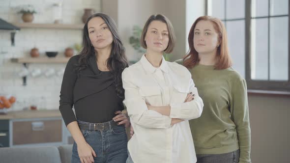 Middle Shot of Three Confident Beautiful Caucasian Women Standing Indoors Looking at Camera