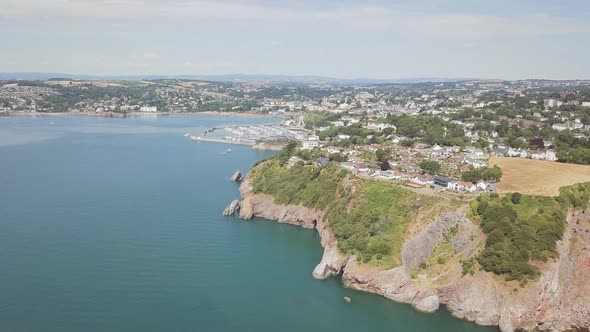 Flying over beautiful beach town in Torquay, England. Coastal town with harbour and Ferris Wheel in