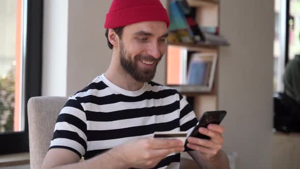 Smiling, positive guy with a beard is shopping online