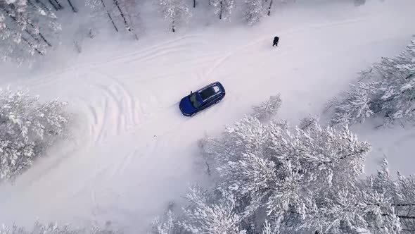Aerial view of a car driving in the snowy forest in Estonia.