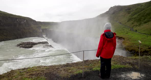 Gulfoss waterfalls in Iceland with gimbal video walking behind woman looking at falls.
