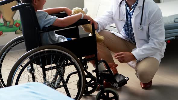 Male doctor interacting with child patient in ward