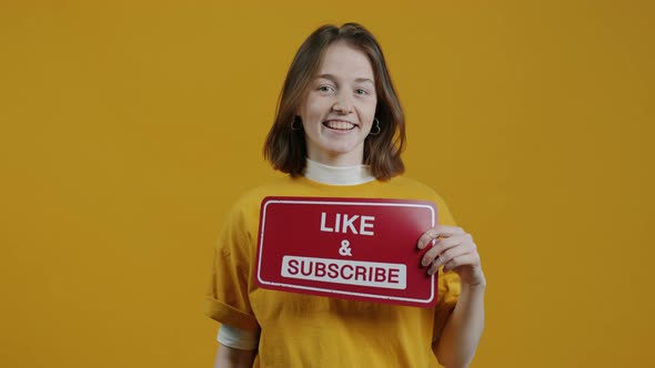 Portrait of Creative Vlogger Pointing at Like and Subscribe Symbol on Yellow Background