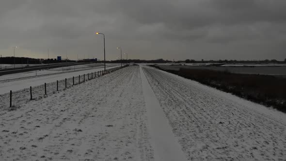 Man Walks On The Middle Of The Snowy Field With Fence Under Overcast. aerial