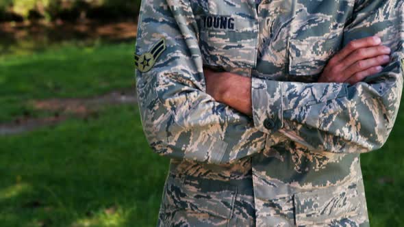 Portrait of soldier standing with arms crossed in park alt