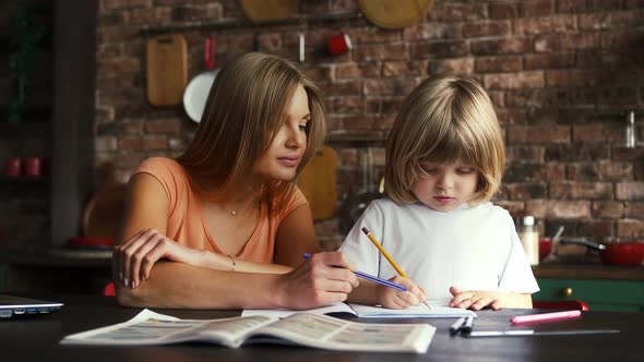 Mum Helping Her Child to Do Homework in School Copybook