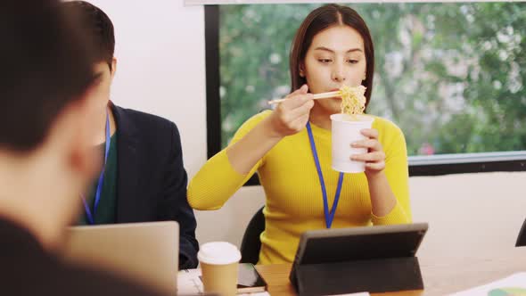 Asia freelance  business woman eating instant noodles while working on laptop