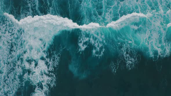 Aerial View Ocean Waves Break Into Foam Along the Shore