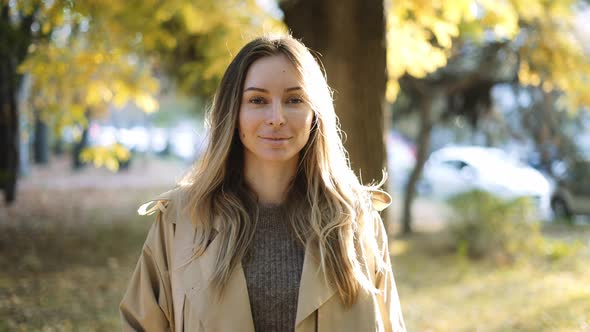 Calm Woman Between Trees in Bright Sunlight on the Background