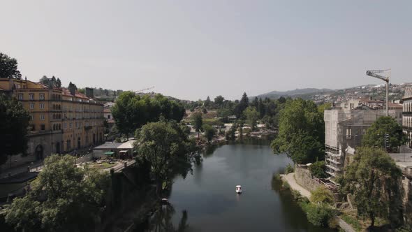 Dolly out shot above tamega river over Sao Goncalo bridge capturing riverside historical buildings.