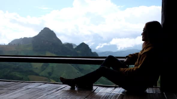 Slow motion of a female traveler sitting and looking at a beautiful mountain and nature view