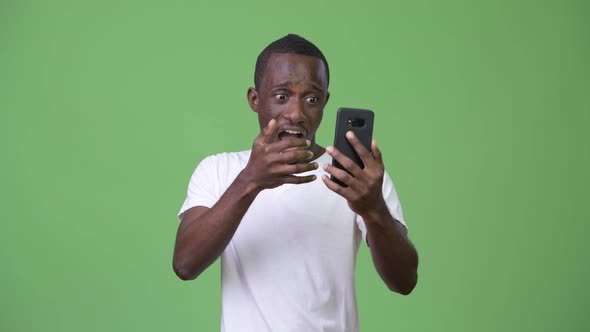 Young African Man Looking Shocked While Using Phone