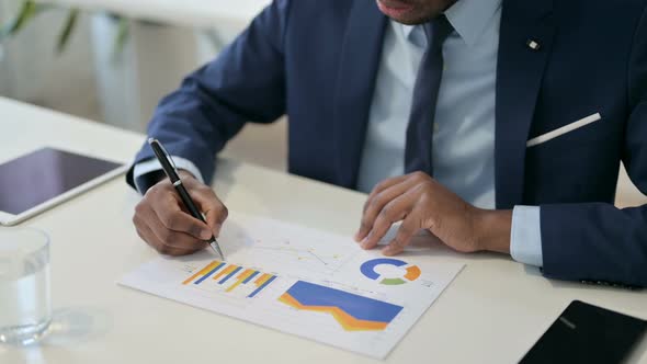 African Businessman Reading Charts on Paper Paperwork