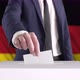 Voting. Man Putting a Ballot into a Voting Box with German Flag on Background. - VideoHive Item for Sale