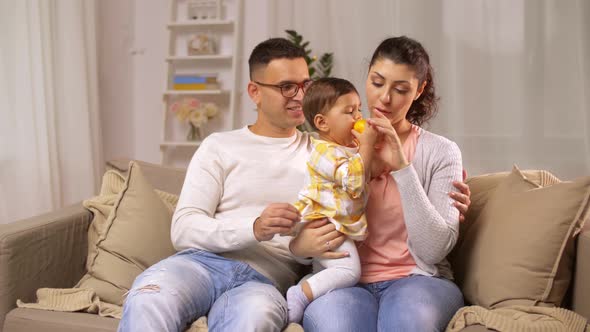 Mother, Father and Baby Eating Orange at Home