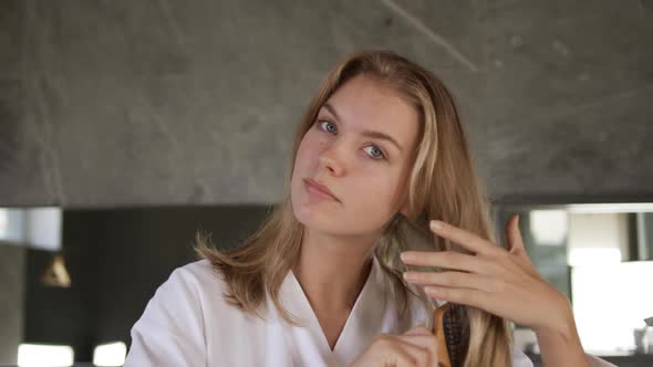 Front view of caucasian woman brushing hair in hotel