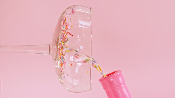 Colorful Candy Confectionery Run Poured Into a Wineglass Glass on Pink Background