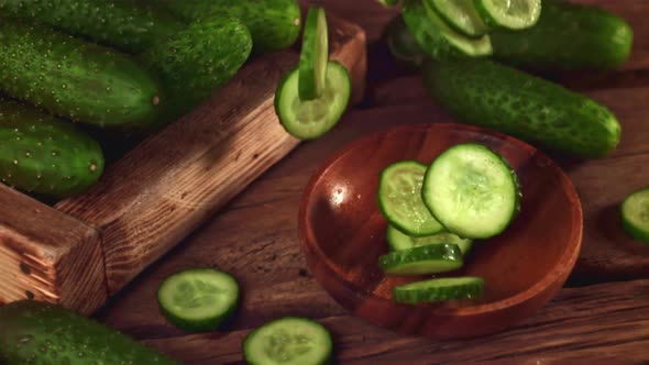 Super Slow Motion Round Pieces of Cucumber Fall Into a Wooden Plate