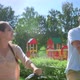 Young Couple Rides a Bicycle Through the Park Against the Background of a Playground - VideoHive Item for Sale