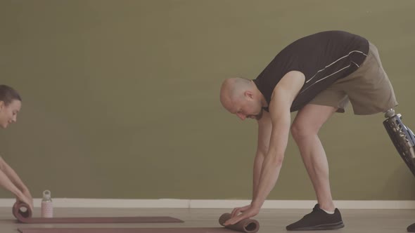 Man with Prosthetic Leg Rolling Up His Yoga Mat after Training