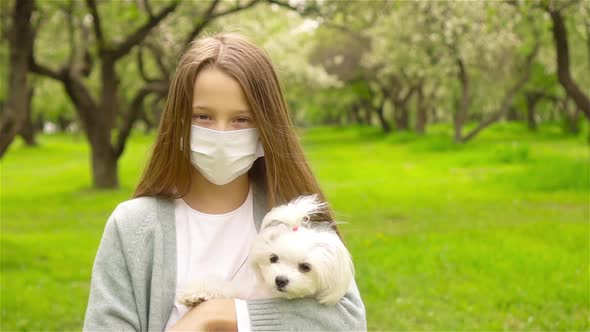 Little Girl with Dog Wearing Protective Medical Mask for Prevent Virus Outdoors in the Park