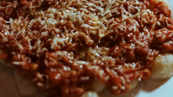 Gnocci with Tomato Sauce Being Sprinkled with Parmesan